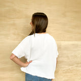White gauze shirt, round neckline, short sleeve, sleeve comes to elbow, frayed edges on the sleeve and bottom, oversized fit
