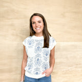 White sweater vest with blue floral detail, white pocket on right side, white detail on the collar and bottom, relax fit