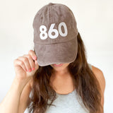 Taupe brown baseball cap, white 860 embroidered on the front, white Anchored American embroidered on the back, leather adjuster strap on the back