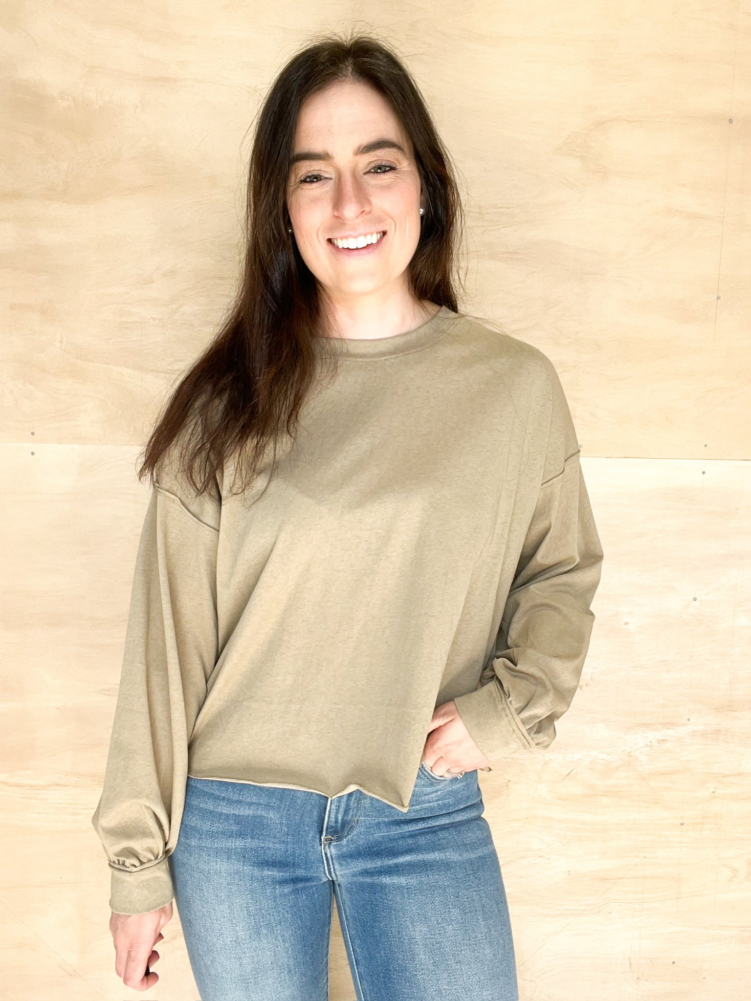 Olive long sleeve, oversized relaxed fit, round neckline, bottom hem is a relaxed frayed