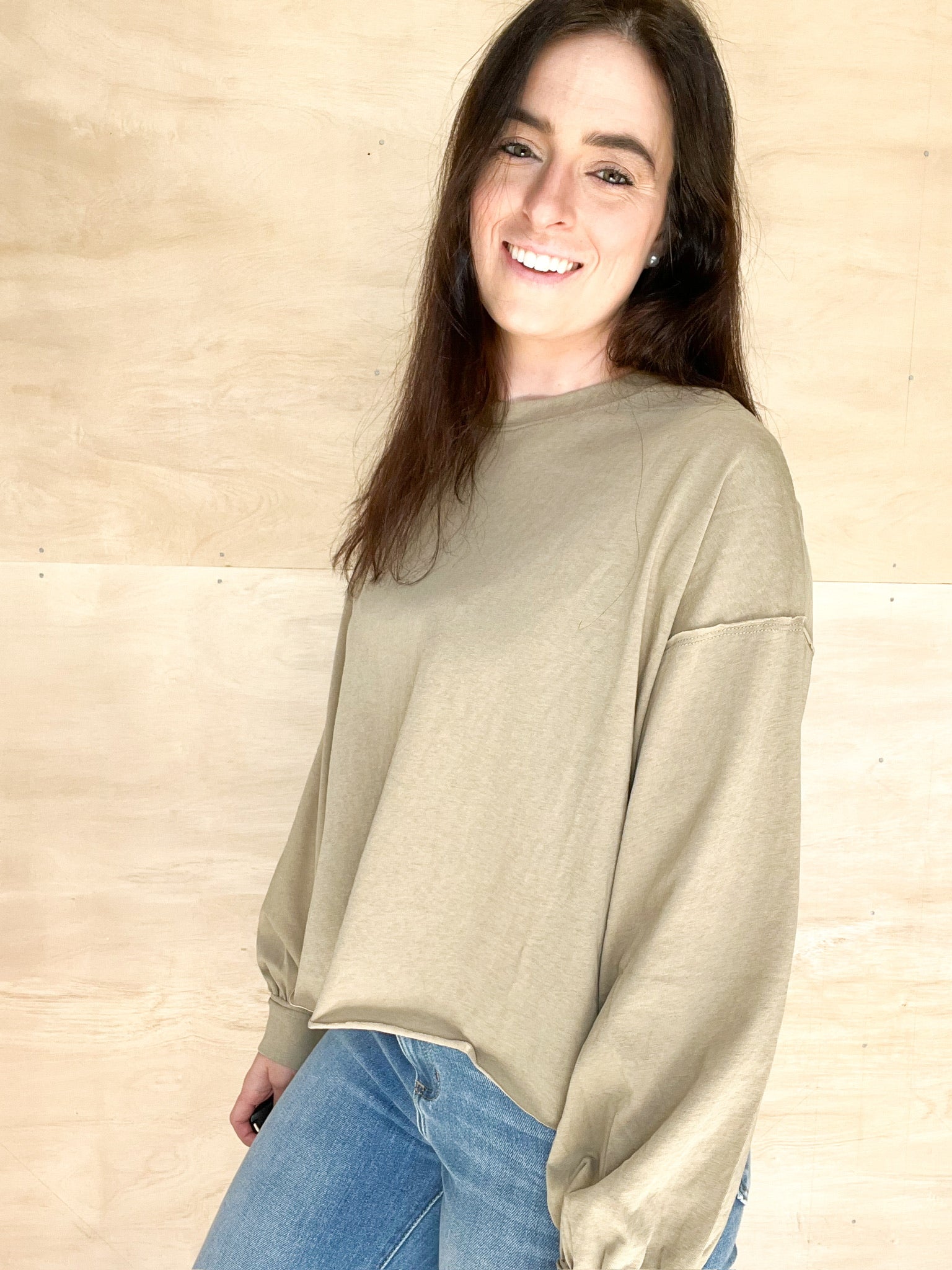Olive long sleeve, oversized relaxed fit, round neckline, bottom hem is a relaxed frayed